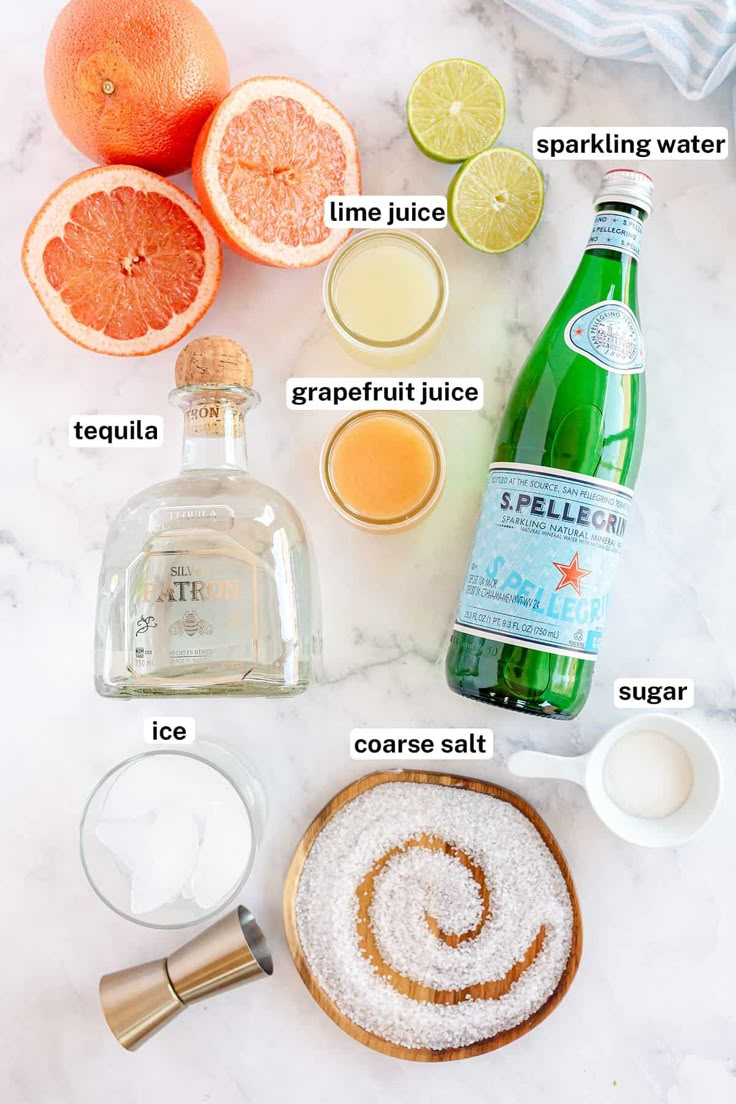 ingredients to make an orange smoothie laid out on a white marble counter top, including grapefruit juice and sugar