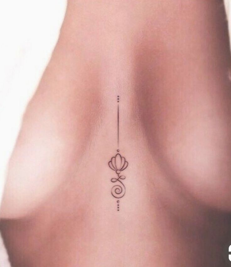 the back of a woman's breast with an arrow tattoo on it