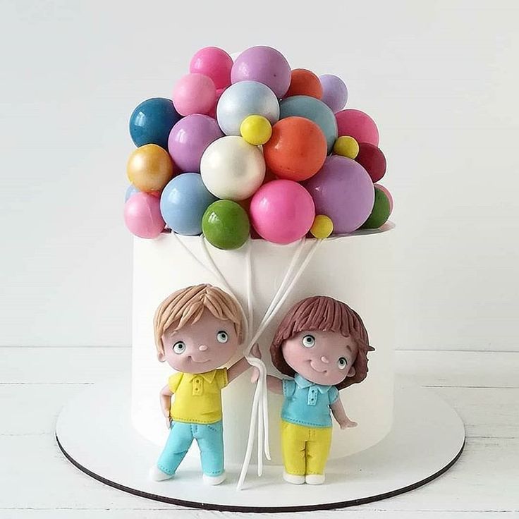 a cake decorated with two children holding balloons