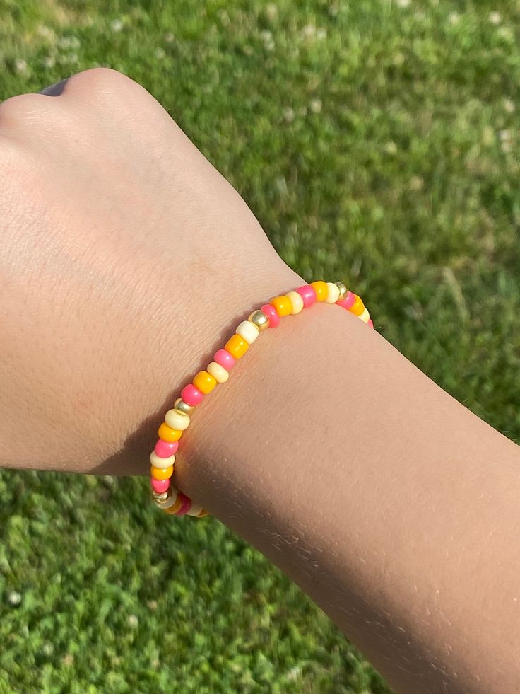 a person's arm with a bracelet made out of candy beads on it in the grass