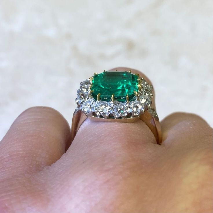 An impressive cluster ring that features a lively 4.55 carat natural Colombian emerald-cut emerald with a green saturation. Surrounding the center stone is a cluster of old European cut diamonds. This ring is crafted in platinum and 18k yellow gold.
The center emerald is GIA certified stating that it is a natural Colombian emerald weighing 4.55 carats and has minor oil treatment.
The total approximate weight of the diamonds is 1.50 carats.
This ring can be resized to any finger size at no extra Colombian Emerald Ring, European Cut Diamond Ring, Estate Diamond Jewelry, Columbian Emeralds, Gia Certificate, Emerald And Diamond Ring, Colombian Emeralds, Gemstone Engagement, 18k Yellow Gold Ring