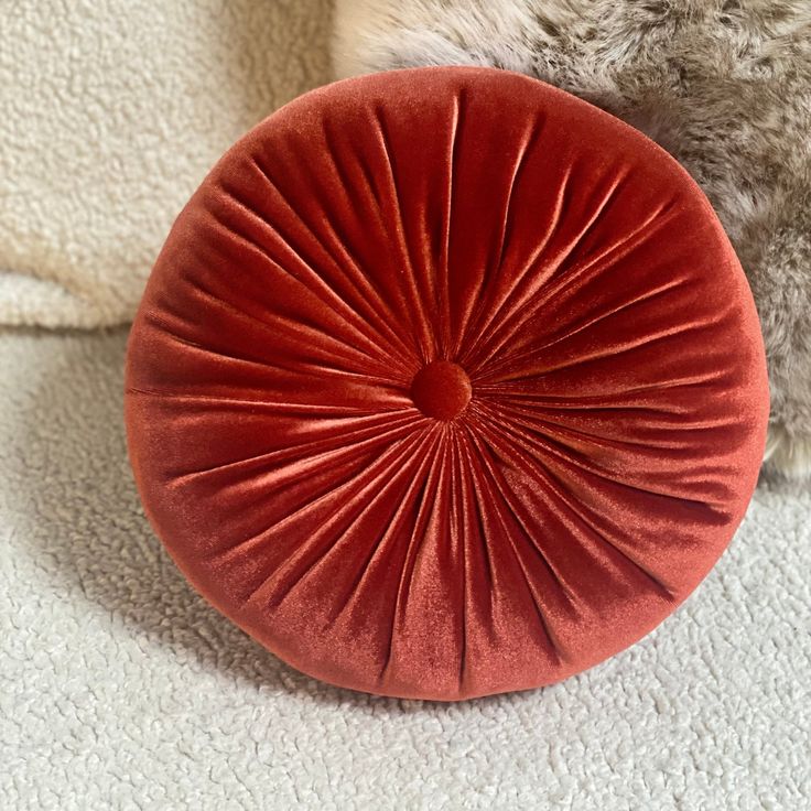 a red round pillow sitting on top of a white carpet