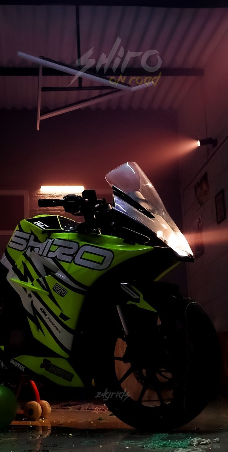 a green motorcycle parked in a garage next to a ball and some lights on the ceiling