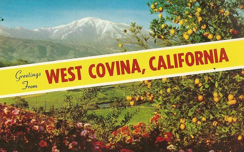 a yellow sign that says west covina, california with mountains in the background