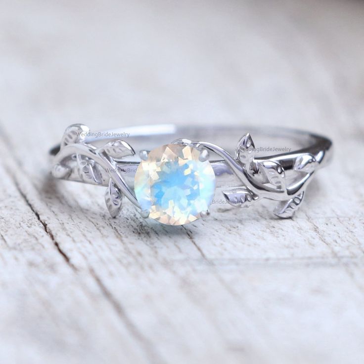 Natural Rainbow Moonstone Engagement Ring Solid 14k White Gold Inspired Moonstone Leaf Ring Bridal Jewelry Everyday Wear Jewelry Gift Ring ≫ Features * SKU : SKU-0054 * Gemstone : 100% Rainbow Moonstone  * Gemstone Weight : 1.00 cts * Gemstone Color : Blue  * Gemstone Quality : AAA * 14K Solid White Gold, ( Available in 14K & 18K Yellow, Rose, and White Gold ) * Option available in 18K Gold * All size available * Ready to Ship in 1-2 Weeks ≫ FAQ below for more detail. ✦ Sizing We can adjust most items to fit your sizing preferences. Most items can be made to any size and length. Please leave a note at checkout or contact us via Etsy conversation. Even after purchasing the item, you can still ask us to adjust the size or length. We will try our best to fix it if it is possible. ★ Rings also Opal Birthstone Ring In White Gold, 14k White Gold Moonstone Promise Ring, 14k White Gold Round Cut Moonstone Ring, White Gold 14k Moonstone Ring, White Gold 14k Gold Round Cut Moonstone Ring, Silver Opal Birthstone Ring In 14k Gold, Silver Opal Ring In 14k Gold, Ethereal Opal Gemstone Ring For Gift, Ethereal Opal Ring As Gift