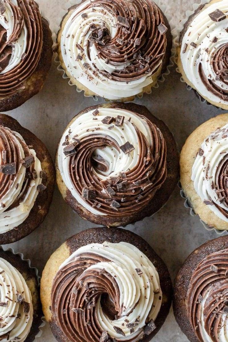 several chocolate cupcakes with white frosting on a baking sheet, top view