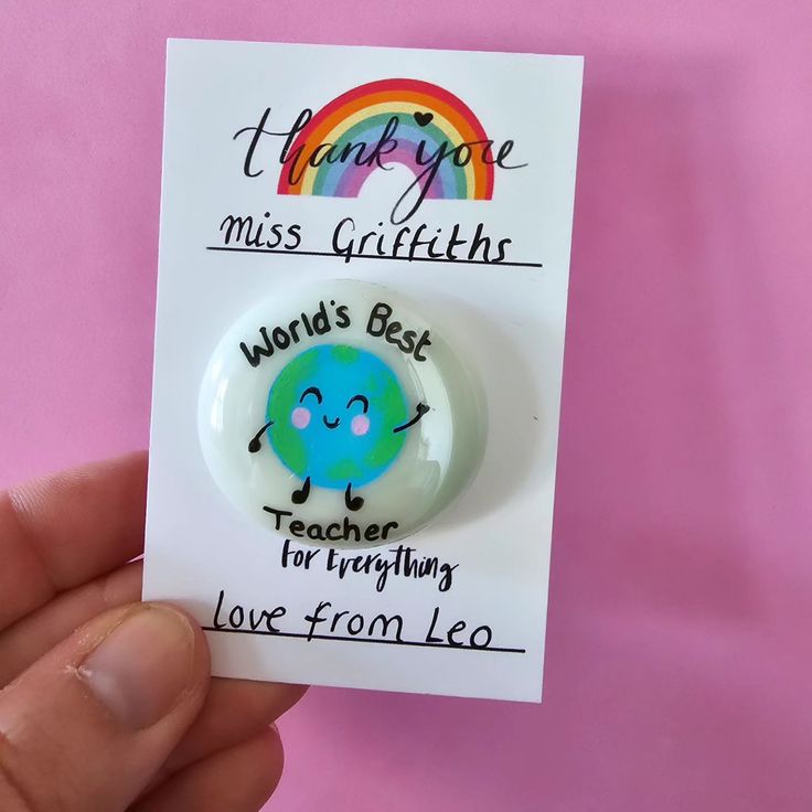 a hand holding a button that says, thank you miss gullither world's best teacher for everything love from leo