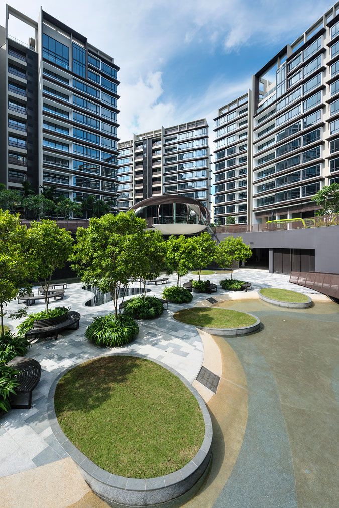 an empty park with benches and trees in front of tall buildings