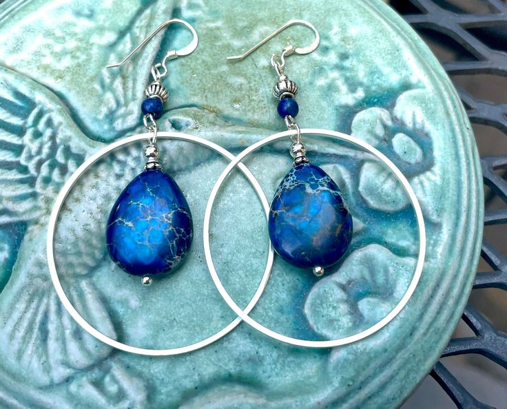 Silver hoop earrings with blue jasper and lapis lazuli stones. I am over the moon about these beauties! They are large and eye-catching but not too heavy! The stones are royal blue jasper.  These earrings are 2 1/2 inches long and 1 1/2 inches wide. The French  earwires are sterling silver.  All my jewelry comes gift boxed with a custom Shelly Mariposa Design butterfly card ready for gift giving, whether it is a gift for you or someone special. Your satisfaction is very important to me. I make e Blue Gemstone Hoop Earrings, Blue Teardrop Gemstone Hoop Earrings, Blue Hoop Jewelry With Natural Stones, Blue Bohemian Hoop Earrings With Natural Stones, Blue Natural Stone Hoop Jewelry, Bohemian Blue Hoop Earrings With Natural Stones, Blue Hoop Earrings With Natural Stones, Blue Natural Stone Dangle Hoop Earrings, Jasper And Lapis