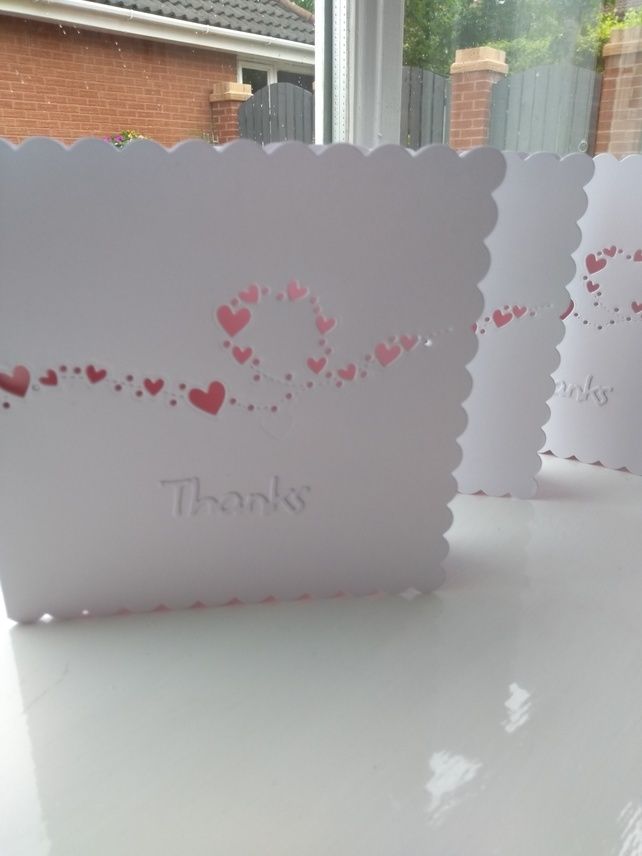 three thank you cards with hearts on them sitting on a table in front of a window