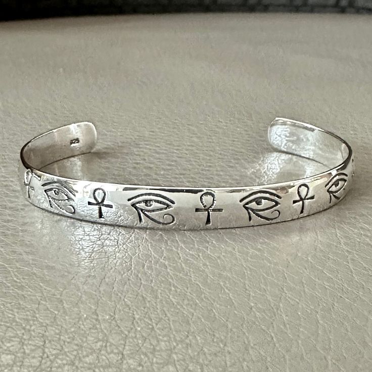 Handcrafted Solid Sterling Silver .925/ Egypt Eye & Ankh Cuff Bracelet 100% hand-polished solid sterling silver Inside bracelet diameter 6.5cm/ 2.56 inches Bracelet opening 4.0cm/ 1.58 inches Approximate weight 14.4 grams Egypt eye & Ankh bracelet crafted in solid 925 sterling silver. The bracelet have a 925 stamp on the inside. Eye of Horus, in ancient Egypt, symbol representing wisdom, protection, health, and restoration. While, Ankh referred to as the key of life or the key of the nile--is re Horus God, Egypt Eye, Life In Ancient Egypt, Egyptian Cross, Cuff Bracelet Silver, Silver Bracelets For Women, Eye Of Horus, Bracelet Crafts, Silver Cuff Bracelet