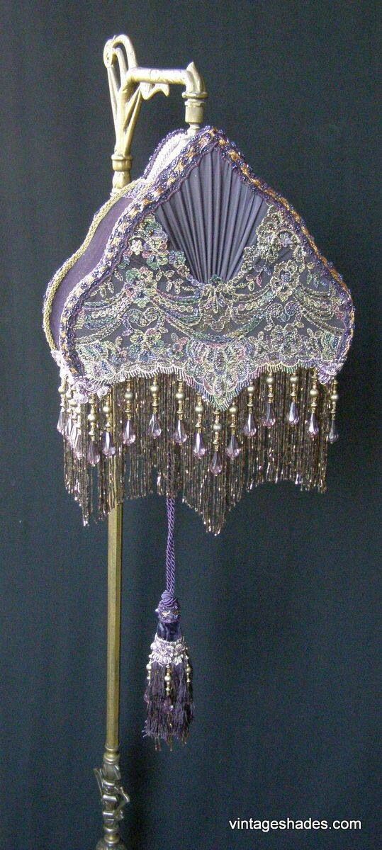 an ornate purple lamp with tassels hanging from it's sides and a fan on top