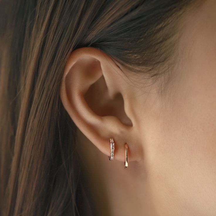 a woman's ear with two small diamond hoop earrings