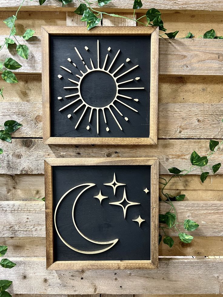 two black and white wall hangings with sun and moon cutouts in wood frames