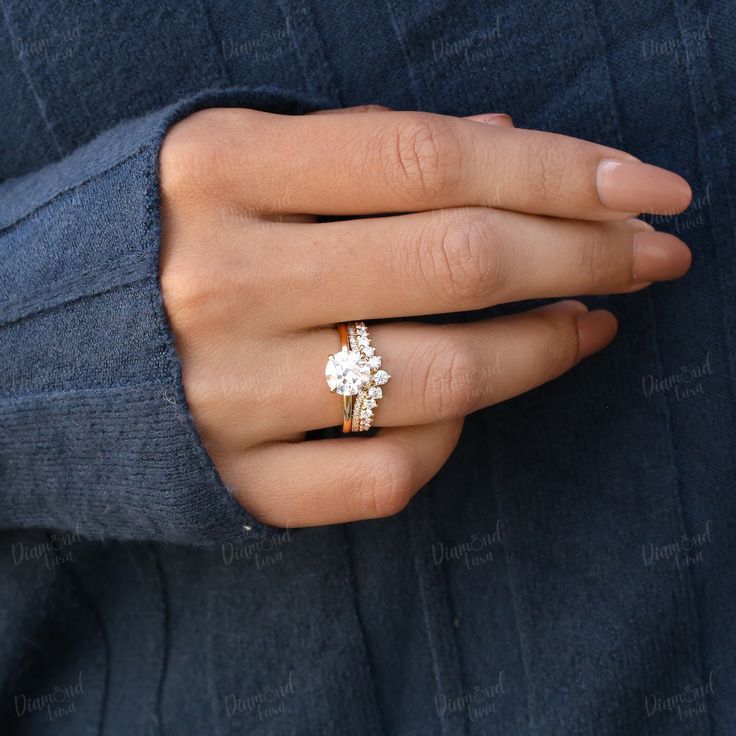 a woman's hand wearing a gold ring with an oval shaped diamond on it