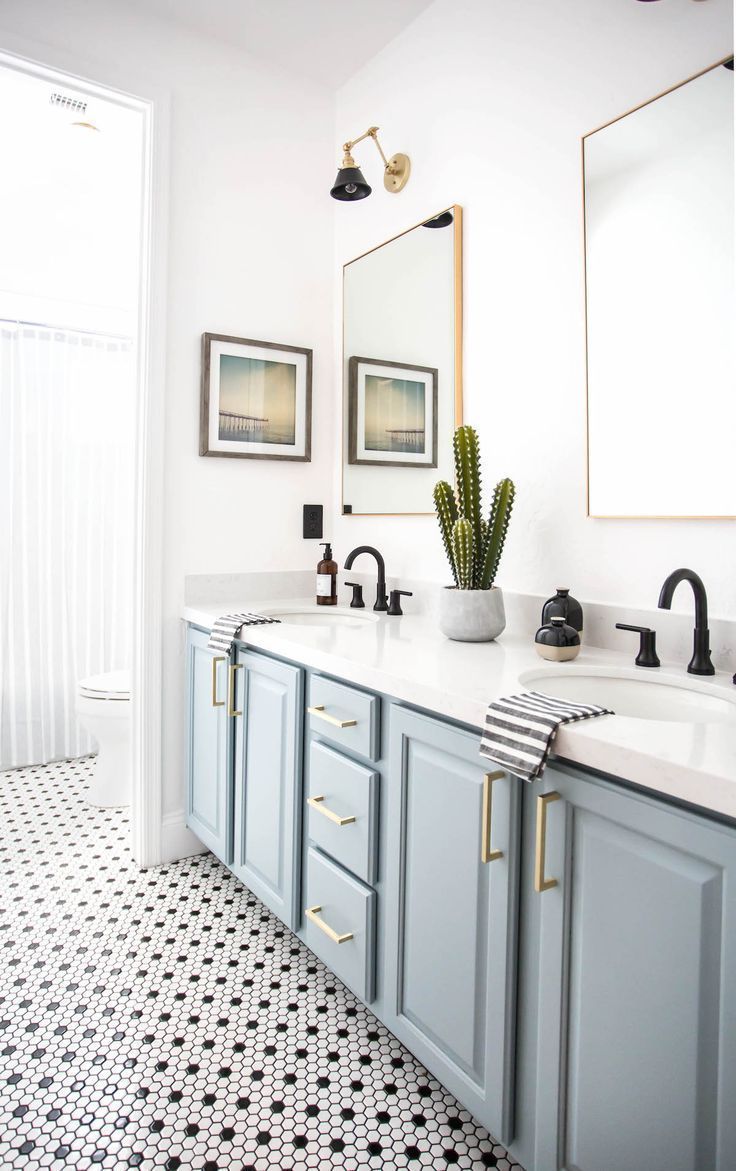 a bathroom with two sinks, mirrors and a potted plant in the middle of the room