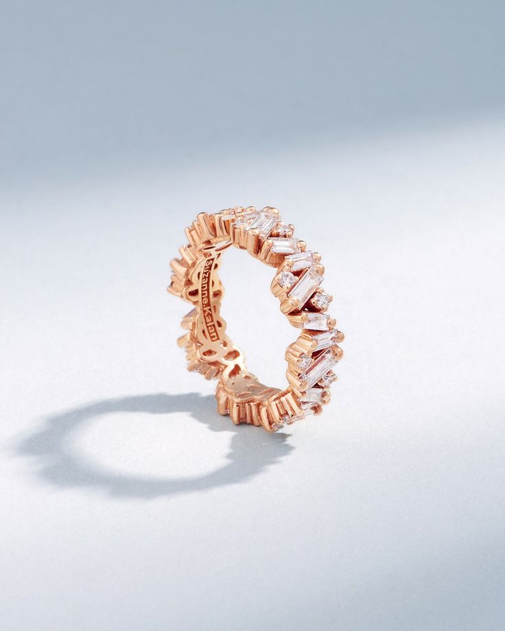 a rose gold ring with three rows of diamonds on the inside and outside, set against a white background