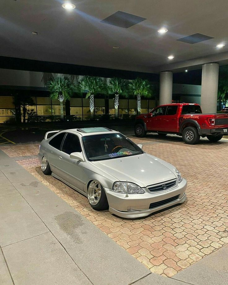 two cars parked next to each other in front of a building with palm trees on it