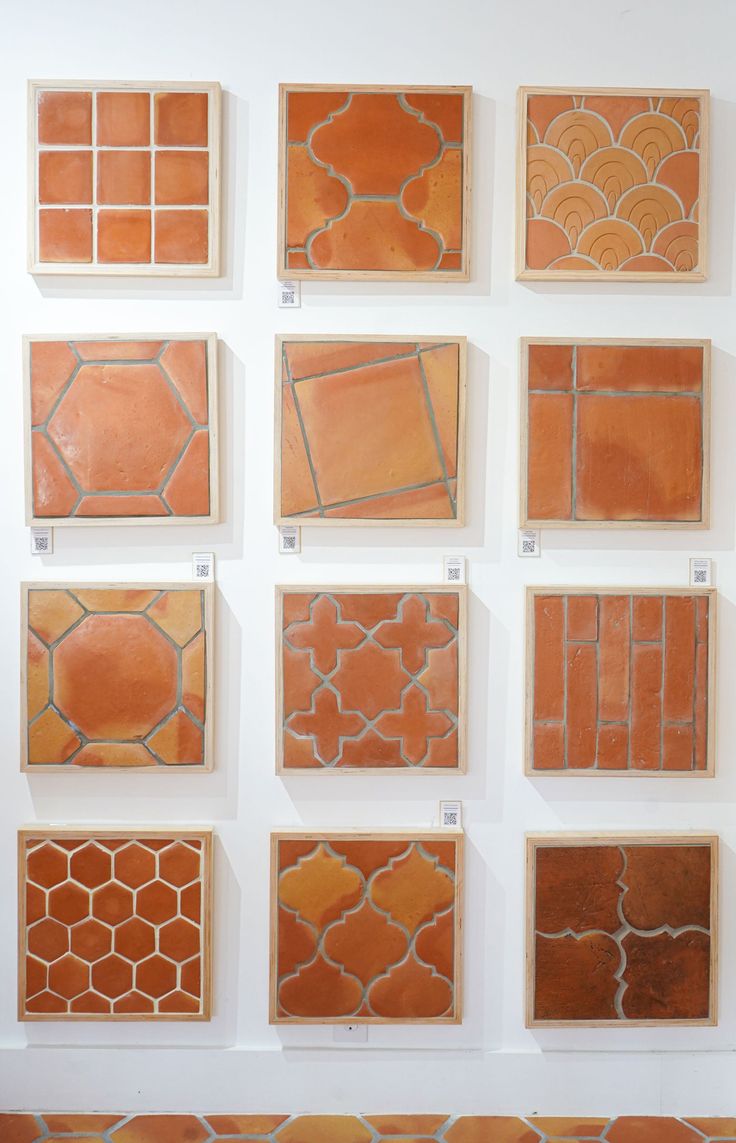 a bunch of different types of tile on display in a white walled room with orange and yellow accents