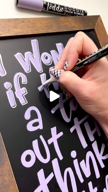 a person is writing on a blackboard with white lettering and a pen in their left hand