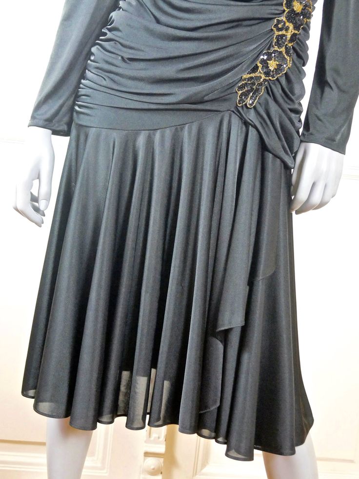 This 1980s American vintage evening dress is the best of Dallas and Dynasty style. The stunning black cocktail dress has a V neckline in the front and back. The bodice has goddess cascades of black material at the front and back of the dress, that drape to below the hipline, opening up to a flared softly pleated skirt that has an additional layer of black material attached. A long jeweled floral appliqué of gold beads and black sequins features on the front bodice. A confident silhouette is guar Vintage Evening Dress, Puffed Long Sleeves, Black Evening Dress, Country Dresses, Black Evening Dresses, Sleeveless Dress Summer, Black Cocktail, Gold Sequin, Floral Applique