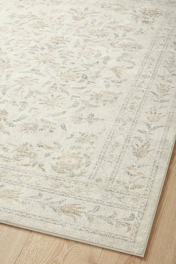 a white rug with an intricate design on the top and bottom, sitting on a wooden floor