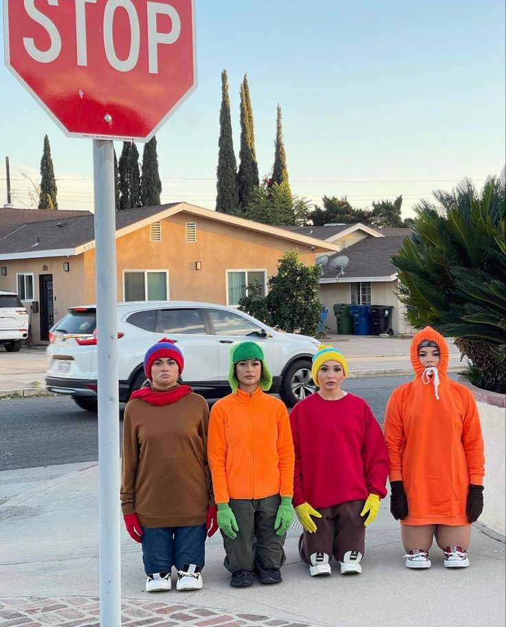 four children in costumes standing under a stop sign