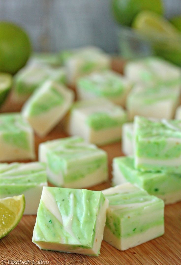 lime and white chocolate fudges cut into squares on a cutting board with limes in the background