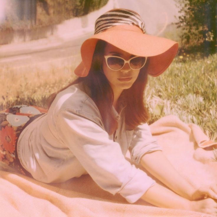 a woman laying on the ground wearing a hat and sunglasses