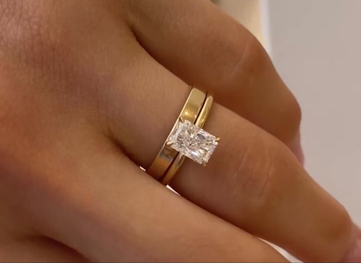 a woman's hand with two gold rings and a diamond ring on her finger