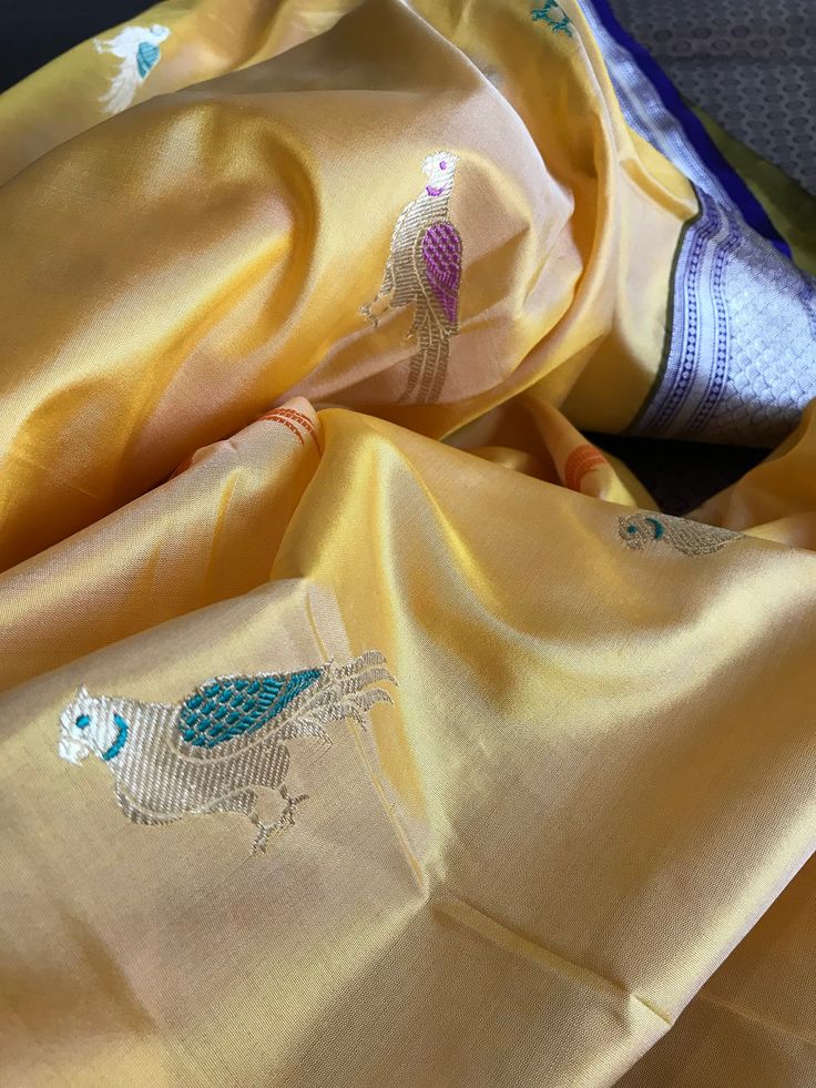 This is a beautiful katan banarasi tissue silk saree in yellow with meenakari parrot motifs all over body and lovely blue borders and pallu. Exquisite silver zari motifs in borders and pallu make them stand out! There are five different shades of parrot motifs in body. Saree comes with an unstitched blouse piece with zari borders. Falls and pico are done. Colour may vary slightly depending on individual device settings. Handloom products may have some irregularities. Dry clean only. All sales ar Yellow Semi-stitched Handloom Saree, Yellow Unstitched Meenakari Saree, Unstitched Yellow Traditional Wear With Meenakari, Semi-stitched Yellow Traditional Wear In Katan Silk, Traditional Yellow Saree With Meenakari, Yellow Wedding Saree With Meenakari, Yellow Banarasi Silk Dupatta With Meenakari, Yellow Motif Dupatta For Navratri, Traditional Yellow Dupatta With Meenakari