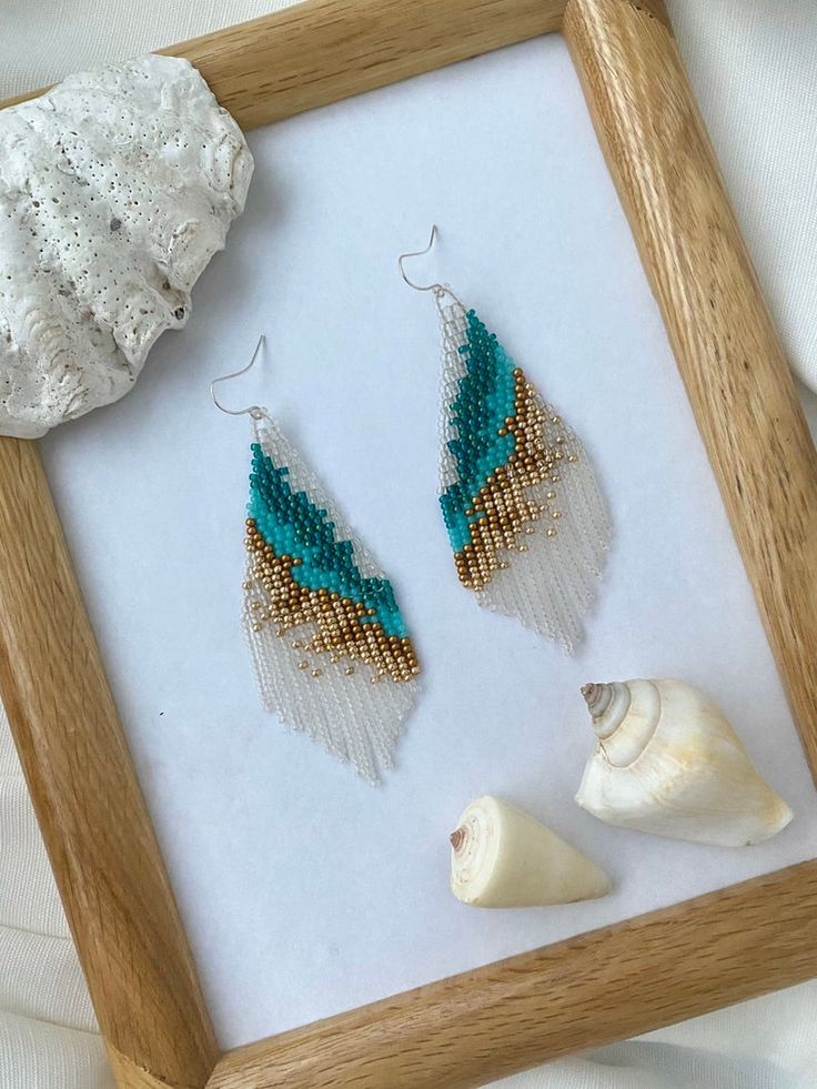 two seashells and one beaded earrings in a frame