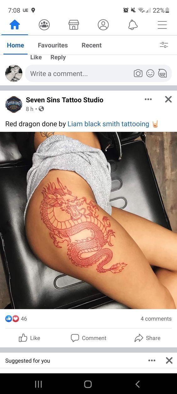 a woman laying on top of a black chair next to a dragon tattooed arm and leg