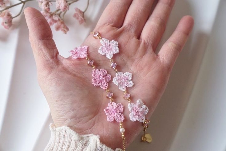 a woman's hand with pink and white flowers on it next to a branch