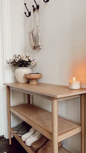 a wooden shelf with shoes and candles on it next to a wall mounted coat rack