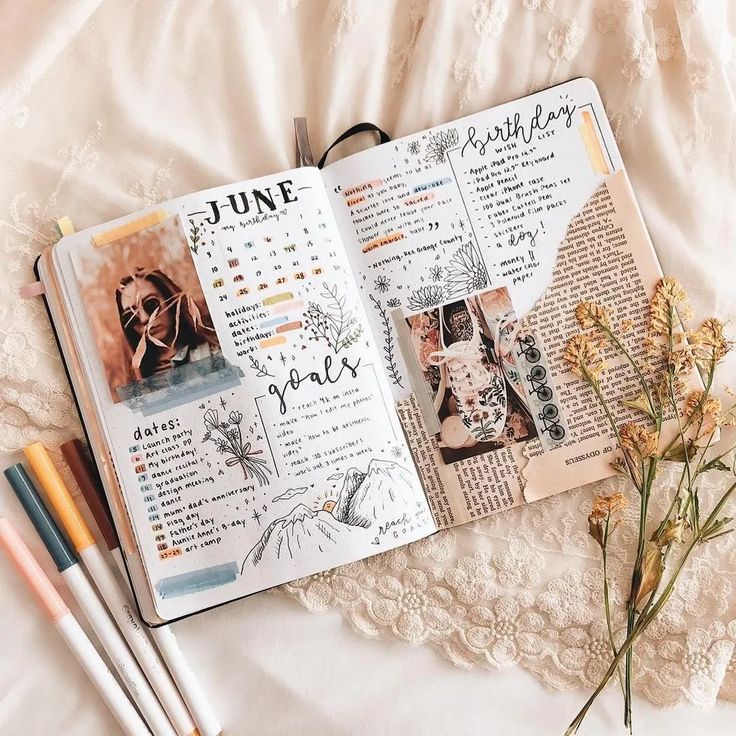 an open book with pictures on it next to some markers and pens, along with flowers