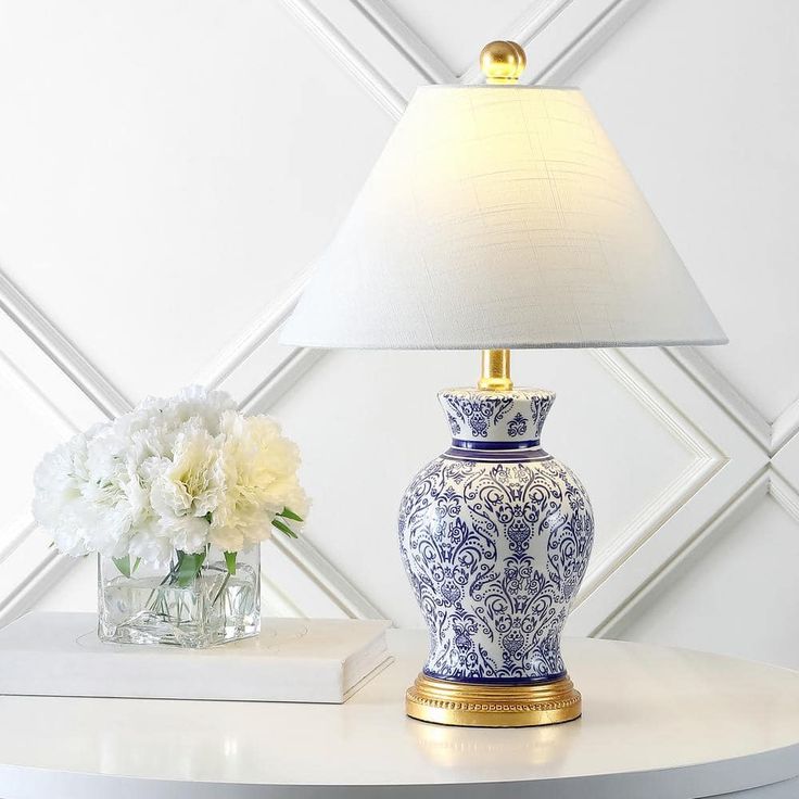 a blue and white vase sitting on top of a table next to a lampshade