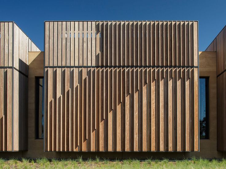 the building has wooden slats on it's sides and is surrounded by grass