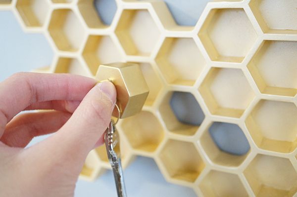 a hand holding a pair of keys in front of a honeycomb wall with hexagons