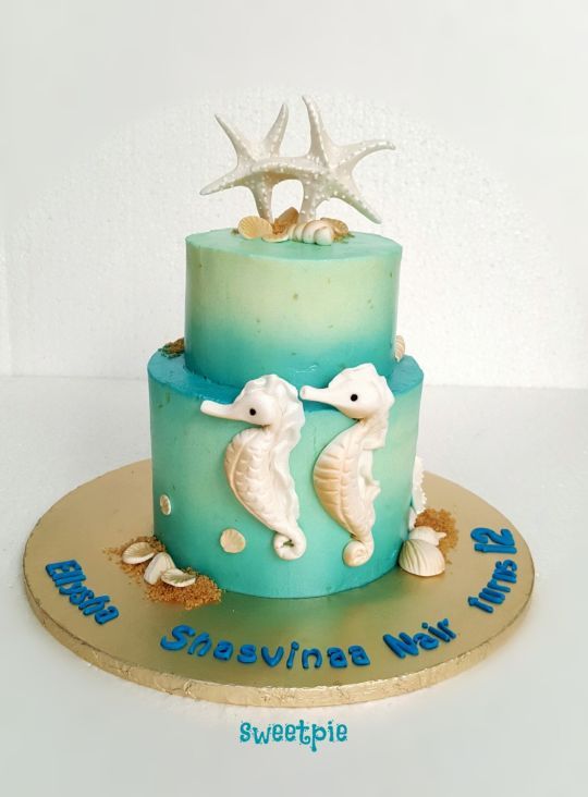 there is a blue and green cake with sea animals on the top, along with two starfishs