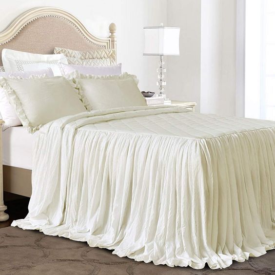 a bed with white sheets and pillows in a bedroom next to a lamp on a table