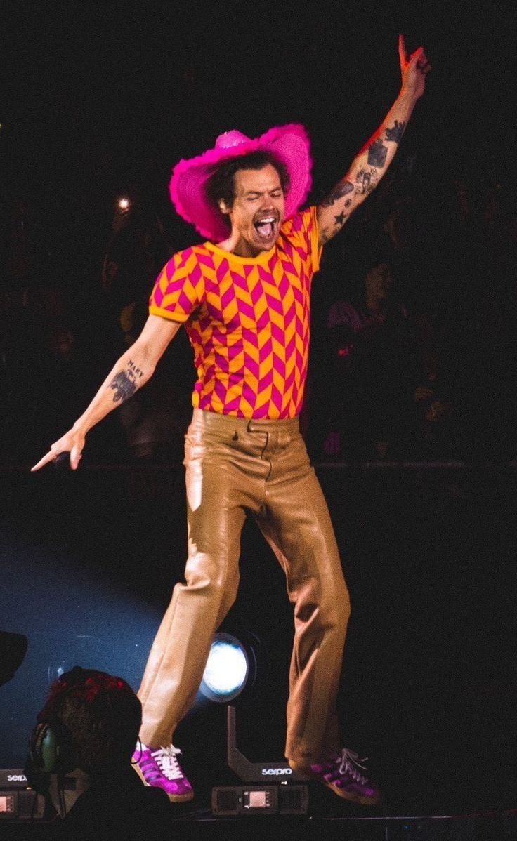 a man with a pink hat on top of his head and arms in the air