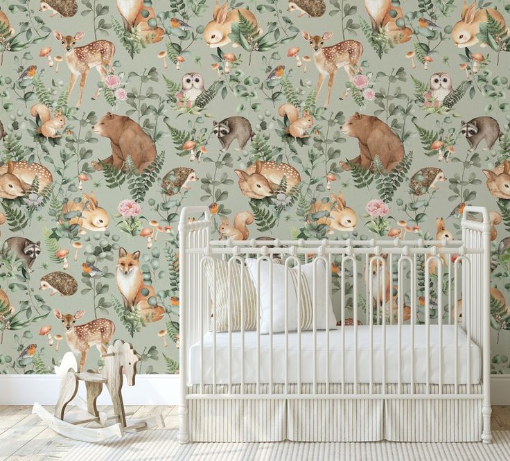 a baby's room with deer wallpaper and a crib in the foreground