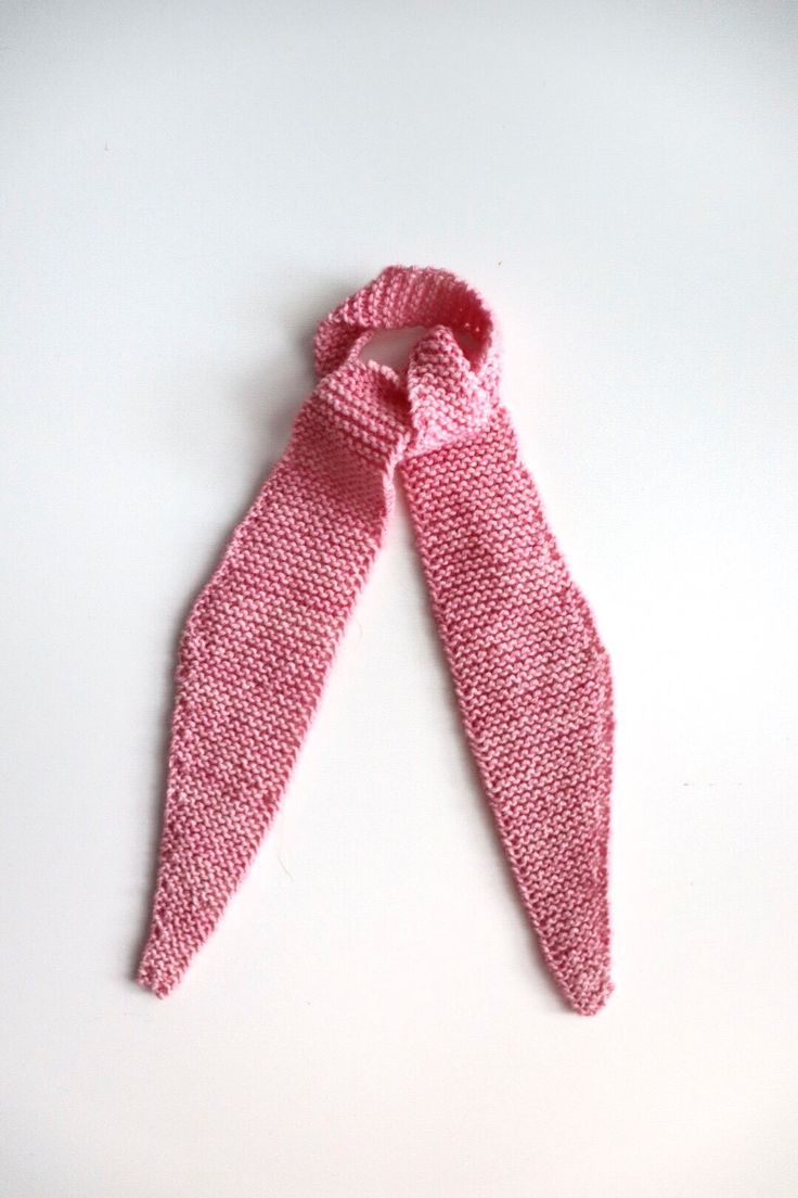 a pink knitted tie laying on top of a white table