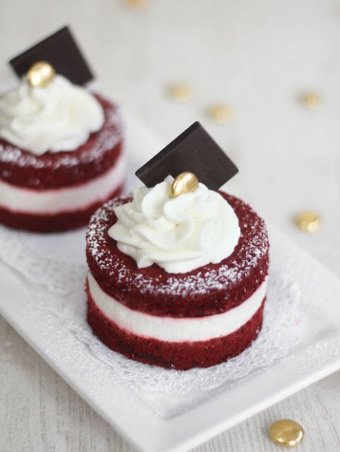 red velvet cake with white frosting and gold decorations on top, then topped with whipped cream