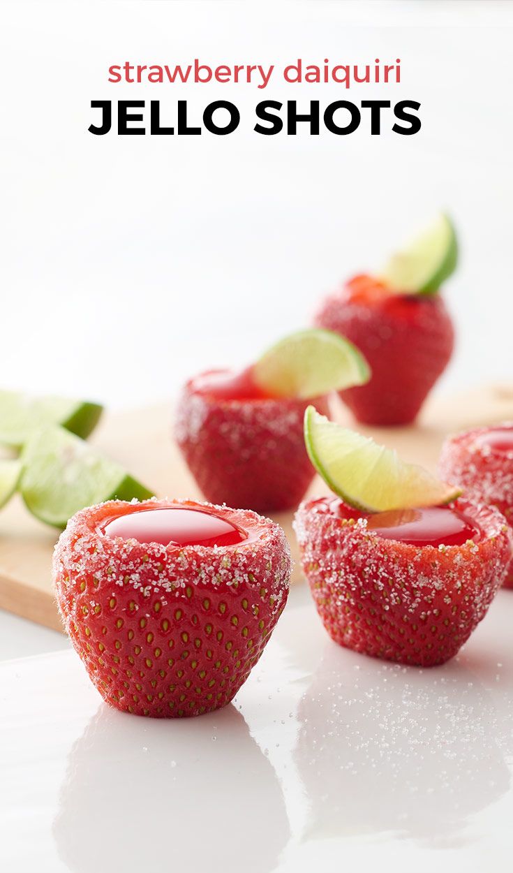 strawberry daiquiri jello shots on a cutting board with limes and strawberries