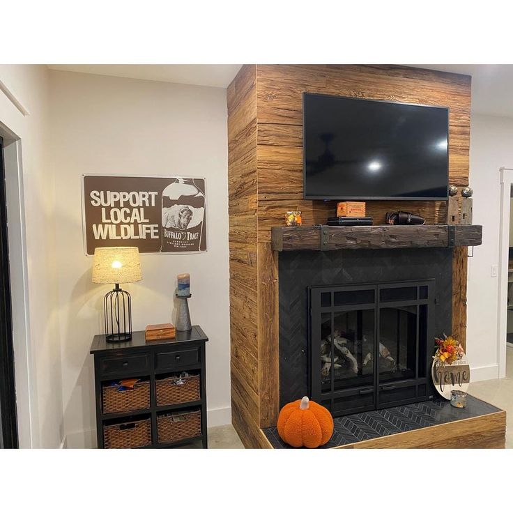 a living room with a fireplace and television mounted on the wall above it is decorated with pumpkins