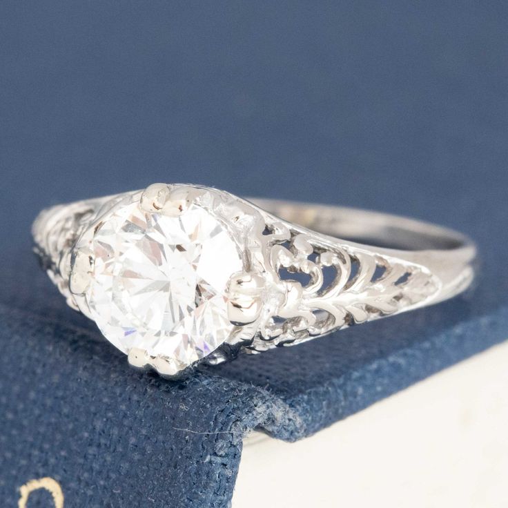 an old - fashioned diamond ring sits on top of a blue velvet book with the word,