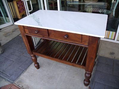 a white marble top table in front of a glass storefront with two drawers on each side