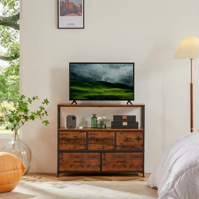 a flat screen tv sitting on top of a wooden dresser next to a large window